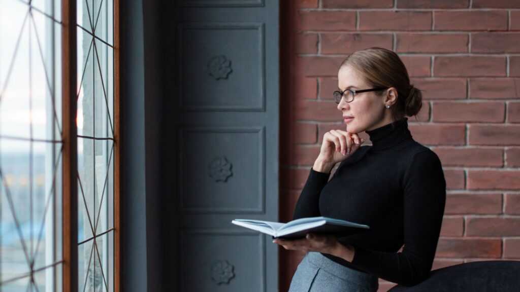 side view woman with book looking window