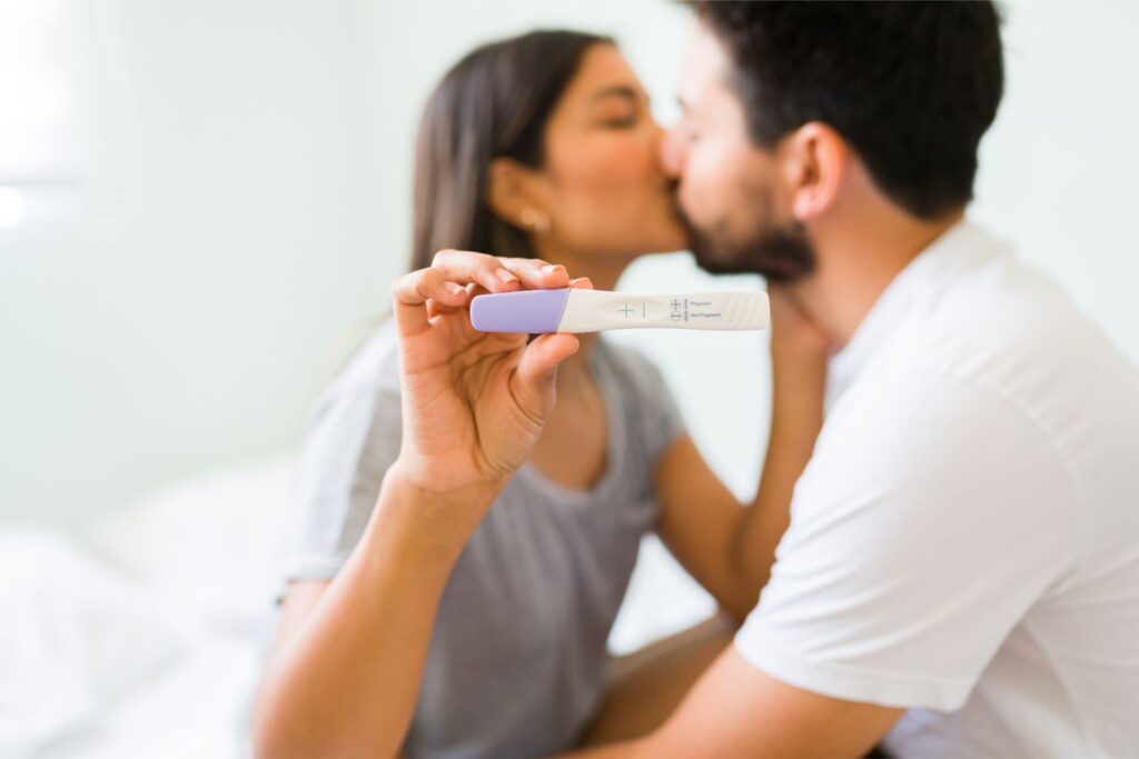 positive pregnancy test latin young woman man love kissing with passion after finding out they are going be parents 1