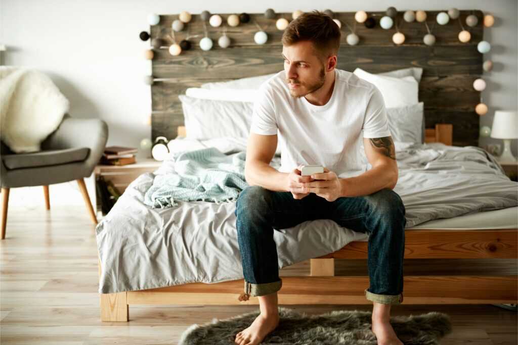 man with mobile phone sitting bed
